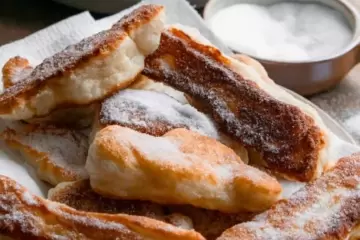 Fried pizza dough strips on a plate covered in white sugar