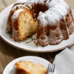 A slice of bundt cake on a plate with a fork. A bundt cake with the piece missing placed behind it.