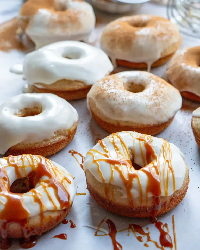 Pumpkin spice donuts with a vanilla frosting and embellished with caramel sauce, or pumpkin pie spice, or they are left plain.