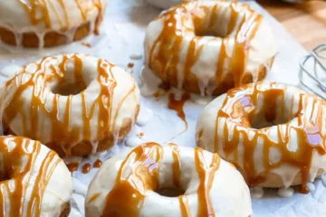 Donuts on a cutting board, the donuts have a vanilla glaze with a caramel sauce drizzle.