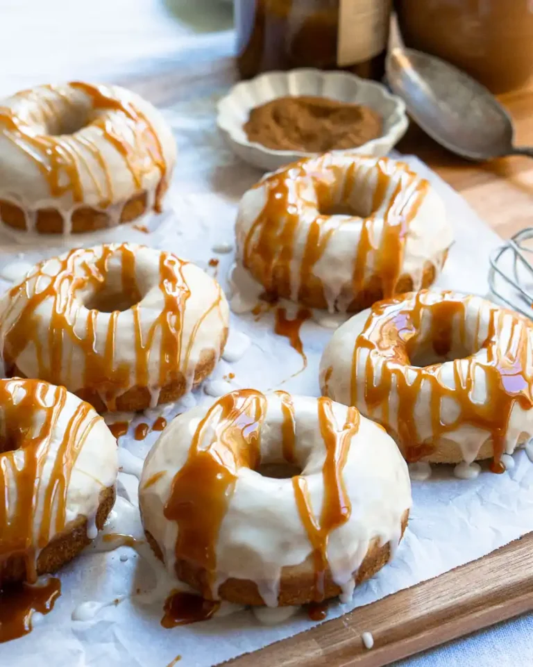 Donuts on a cutting board, the donuts have a vanilla glaze with a caramel sauce drizzle.