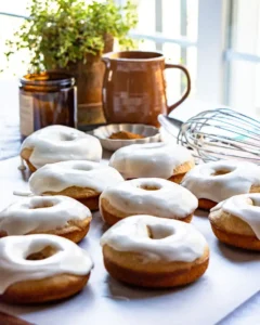 Vanilla glazed donuts sitting on parchment paper.