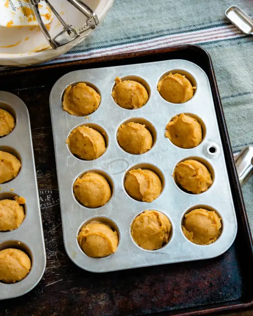 Mini muffin pans filled with unbaked gluten-free pumpkin bites batter.