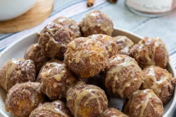 Cinnamon sugar pumpkin bites with a glaze. The pumpkin bites are piled onto a plate.