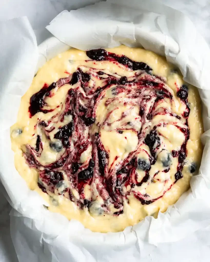 Unbaked blueberry streusel coffee cake with blueberry jam swirled into the batter