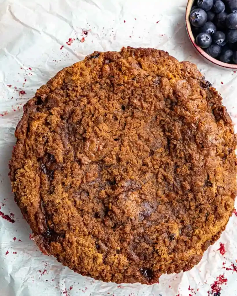 A round baked blueberry streusel coffee cake that is not yet frosted