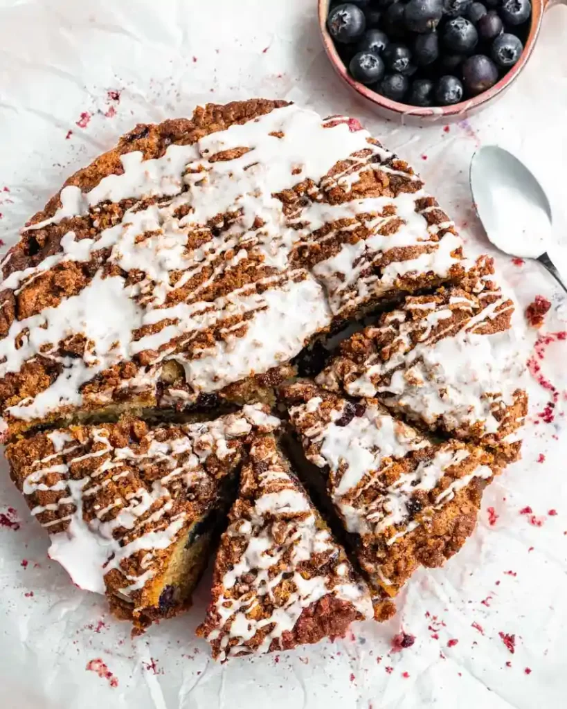 A round coffee cake with a glaze drizzle. The cake is cut in several slices that are slightly pulled away from the main cake