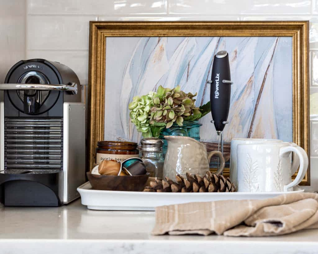 Nesspresso coffee maker, with a tray of coffee mug, pitcher next to it.