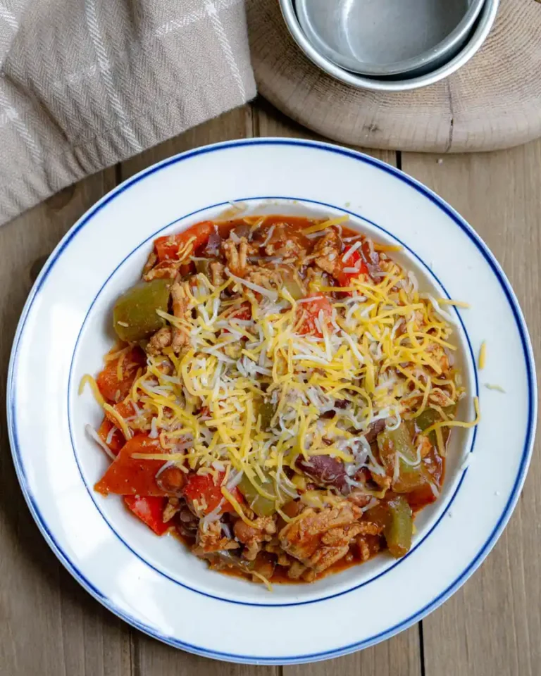 A bowl of chili with shredded cheese on top.