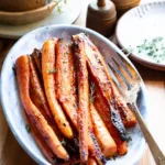 Maple roasted carrots on an oval platter with a serving fork.