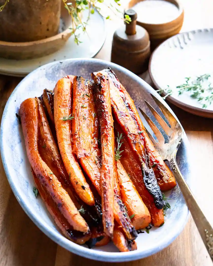 Maple roasted carrots on an oval platter with a serving fork.