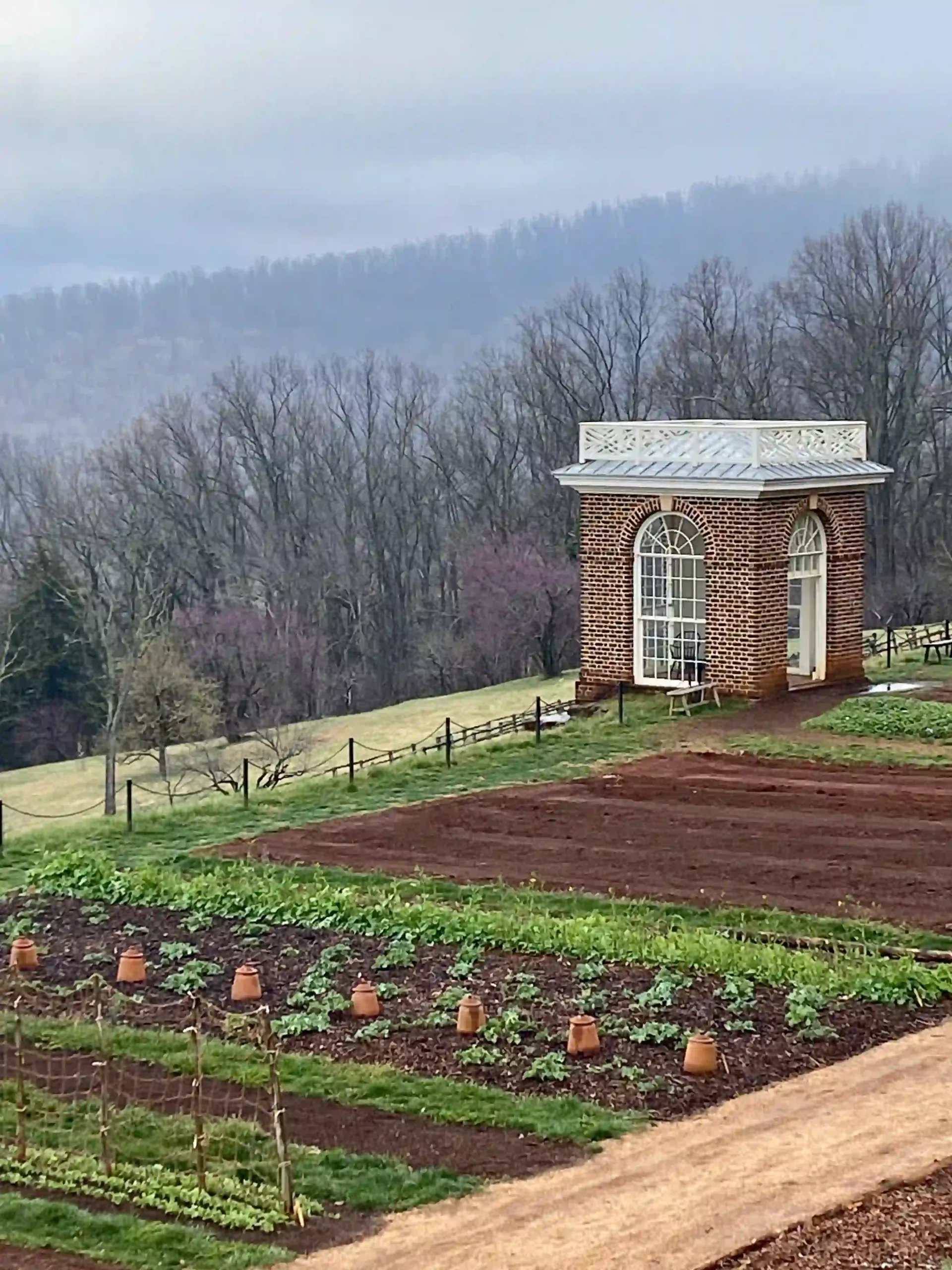 the view of the gardens at Monticello along with rows of plants and little brick pavilion