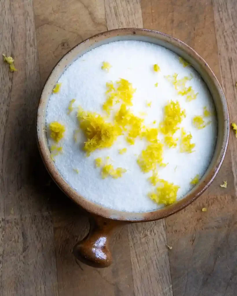 A small bowl of sugar with lemon zest on top of it.