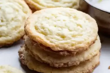 Lemon butter sugar cookies stacked with other cookies nearby