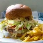 Hamburger with a bun and toppings with a side of fries on a plate