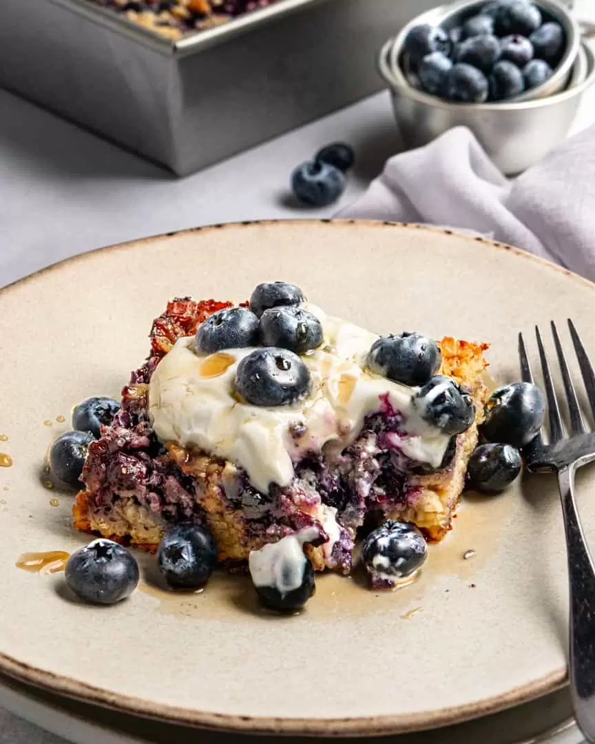 Baked blueberry oatmeal square with toppings and piece missing