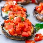 Grilled portobello mushroom with bruschetta on top of it.