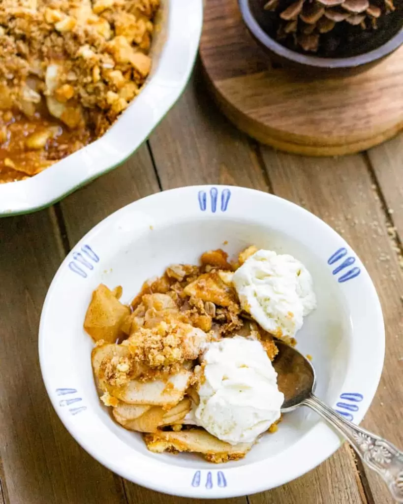 Apple Crips in a bowl with two scoops of ice cream and a spoon