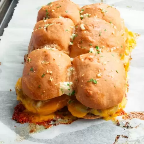 Baked slider buns filled with roast beef and melted cheddar cheese.