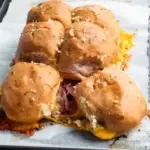 Gluten-free slider buns with two pulled away from the others and melted cheddar between the two buns.