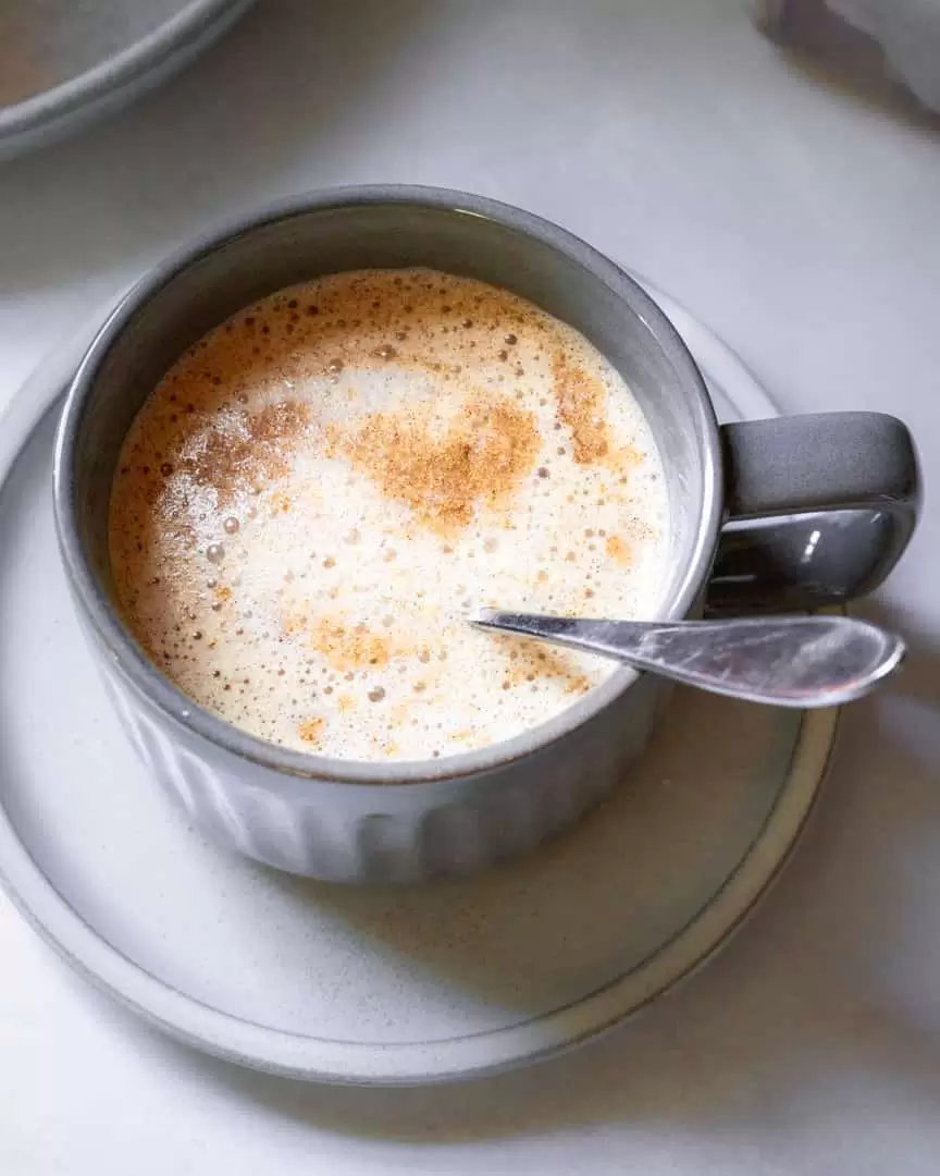 A mug of tea with a spoon in it.