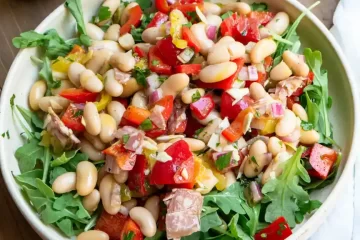 A plate with arugula with Italian Grinder Salad layered on top of the arugula.