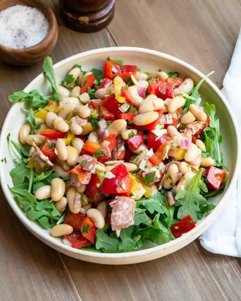 A plate with arugula with Italian Grinder Salad layered on top of the arugula.