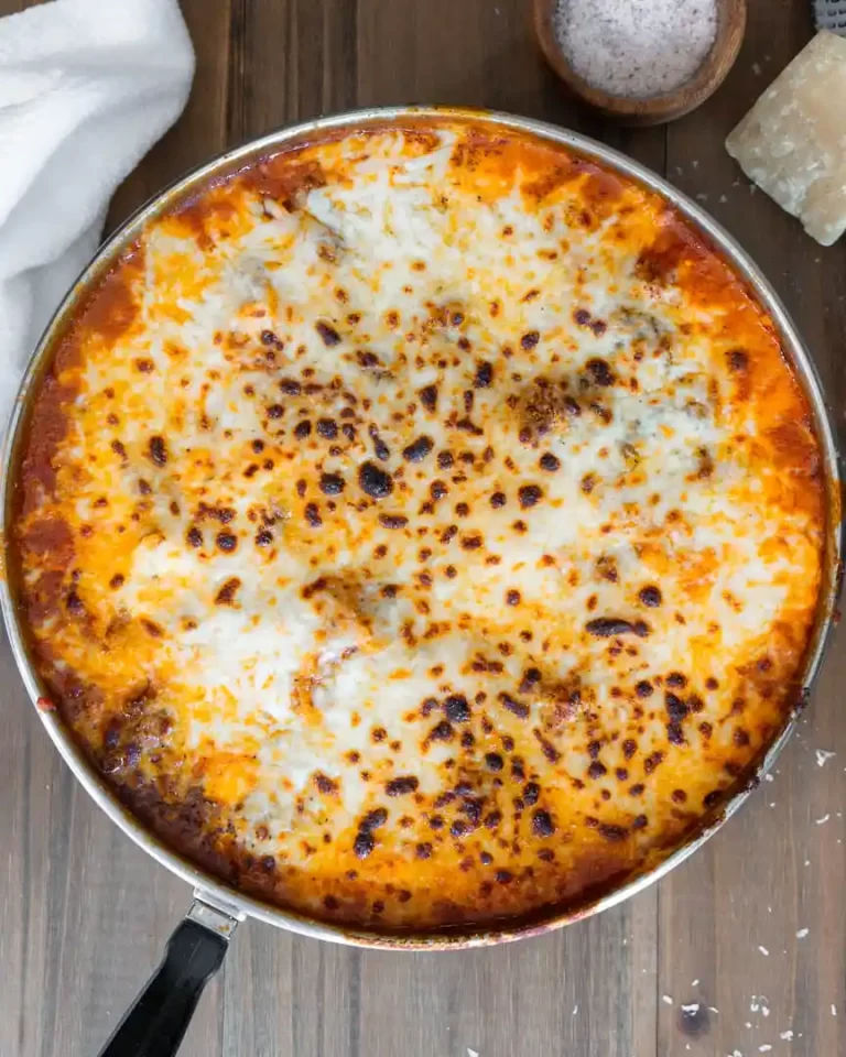 A skillet of lasagna with broiled mozzarella cheese on top.