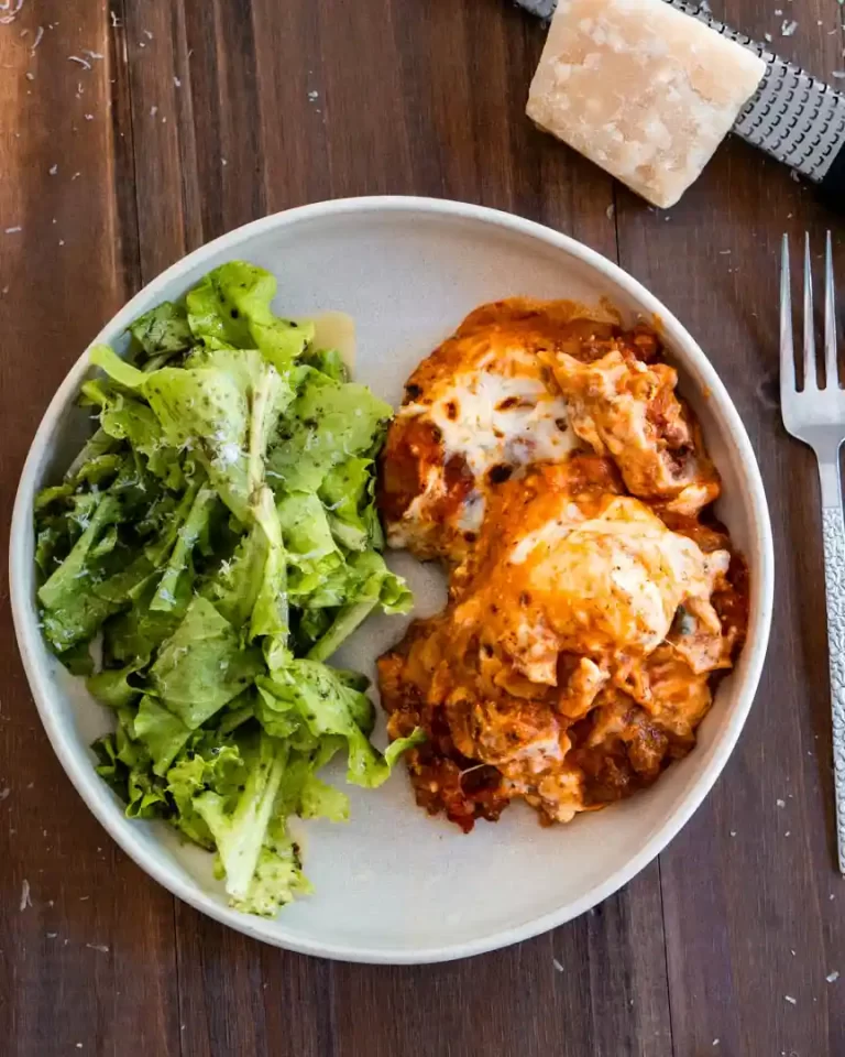 A plate of lasagna with lettuce on the side.