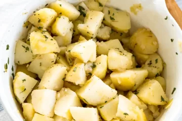 A large bowl filled with bite size pieces of boiled potatoes sprinkled with parsley.