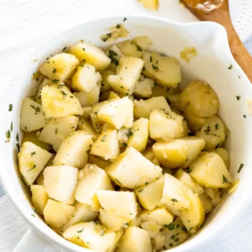 A large bowl filled with bite size pieces of boiled potatoes sprinkled with parsley.