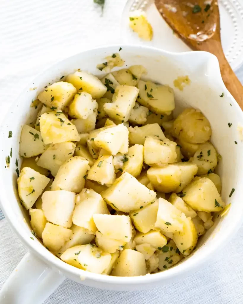 A large bowl filled with bite size pieces of boiled potatoes sprinkled with parsley.