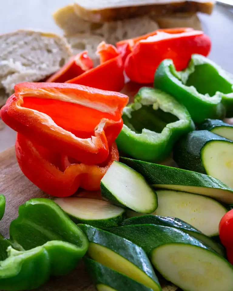 Raw red and green peppers alongside raw zucchini slices on a platter.