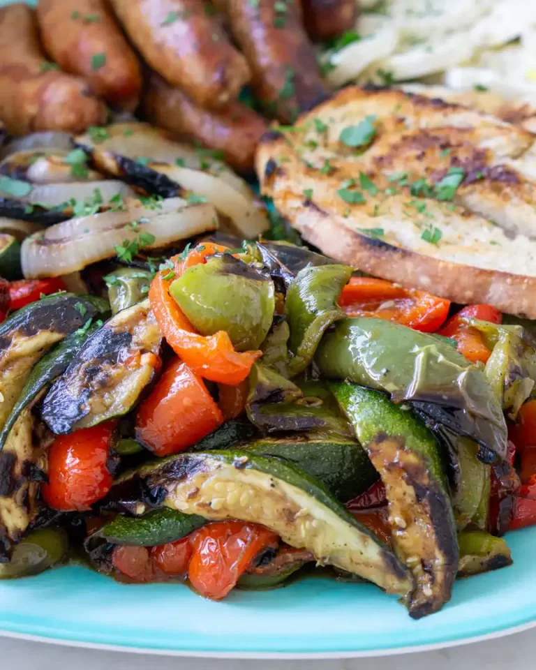 Roasted vegetables on a platter alongside grilled toasted bread.