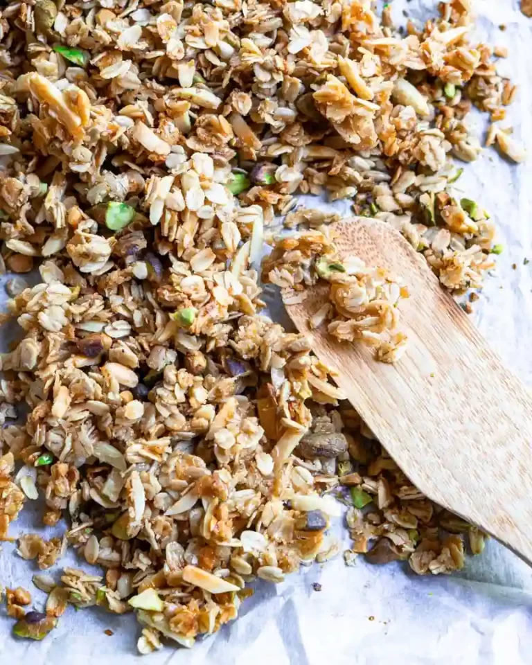 Lemon Pistachio Granola on a baking sheet with a wood spatula on top of the granola