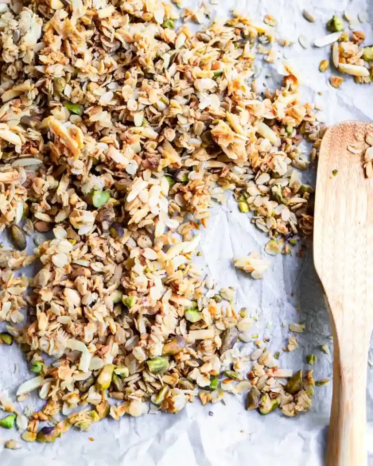 Granola on a baking sheet with a wood spatula off to the side.