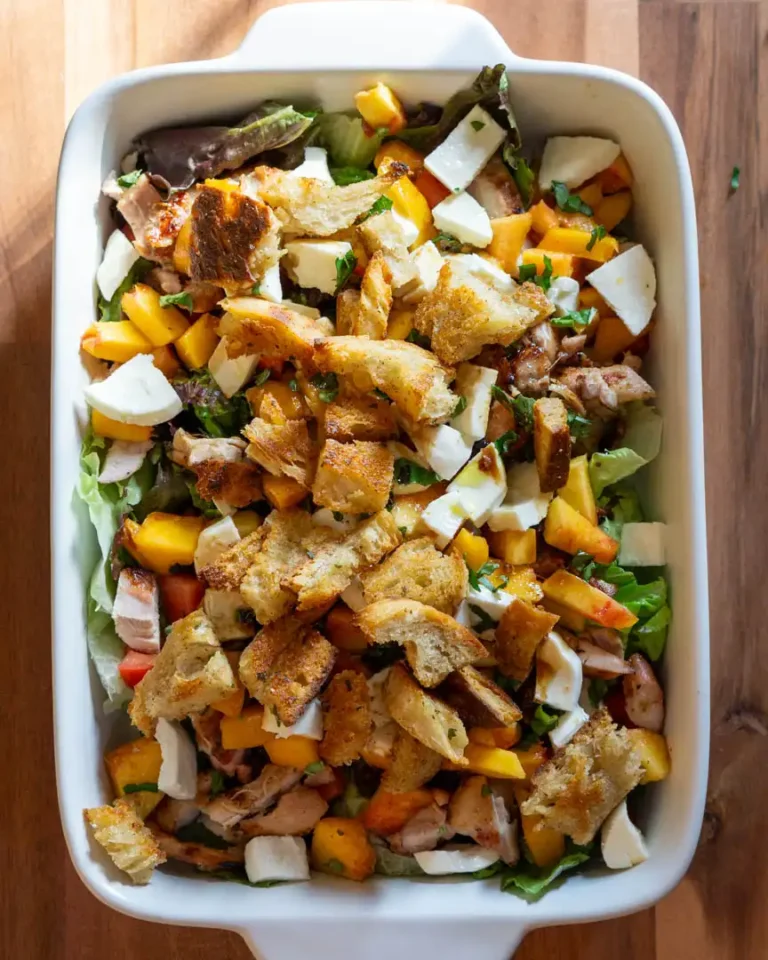 A baking pan with grilled chicken and peaches salad.