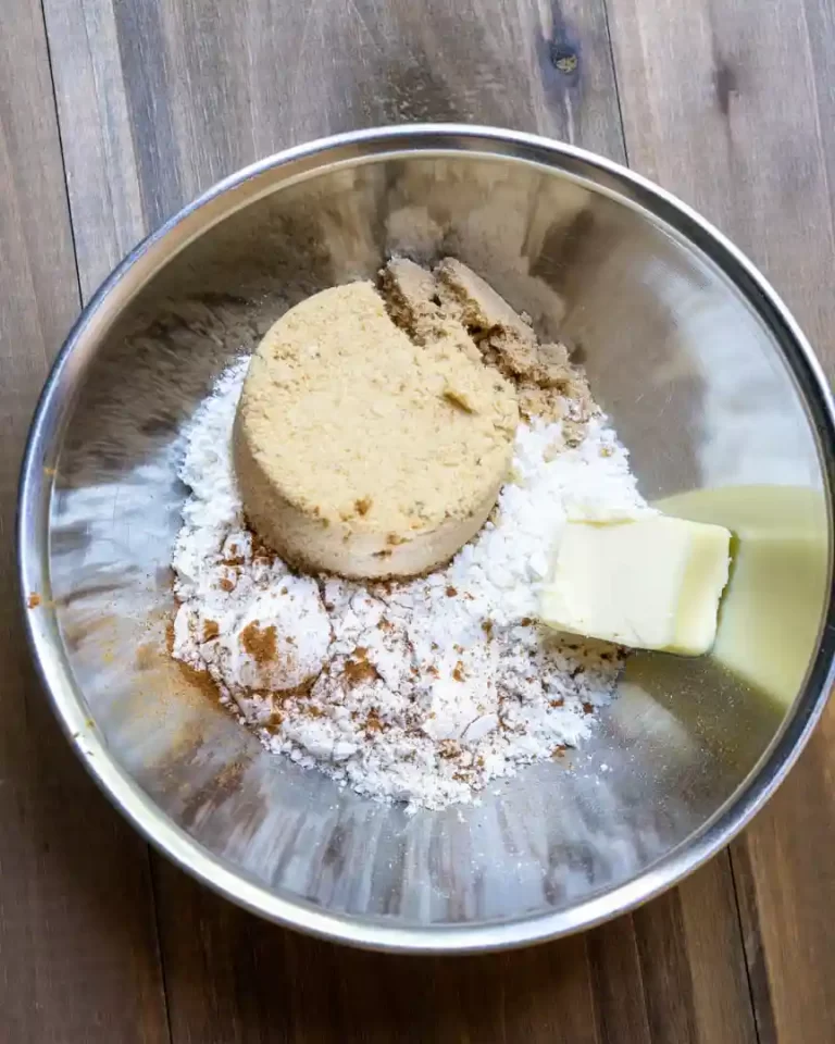 A round bowl with flour, brown sugar, and a cube of butter.