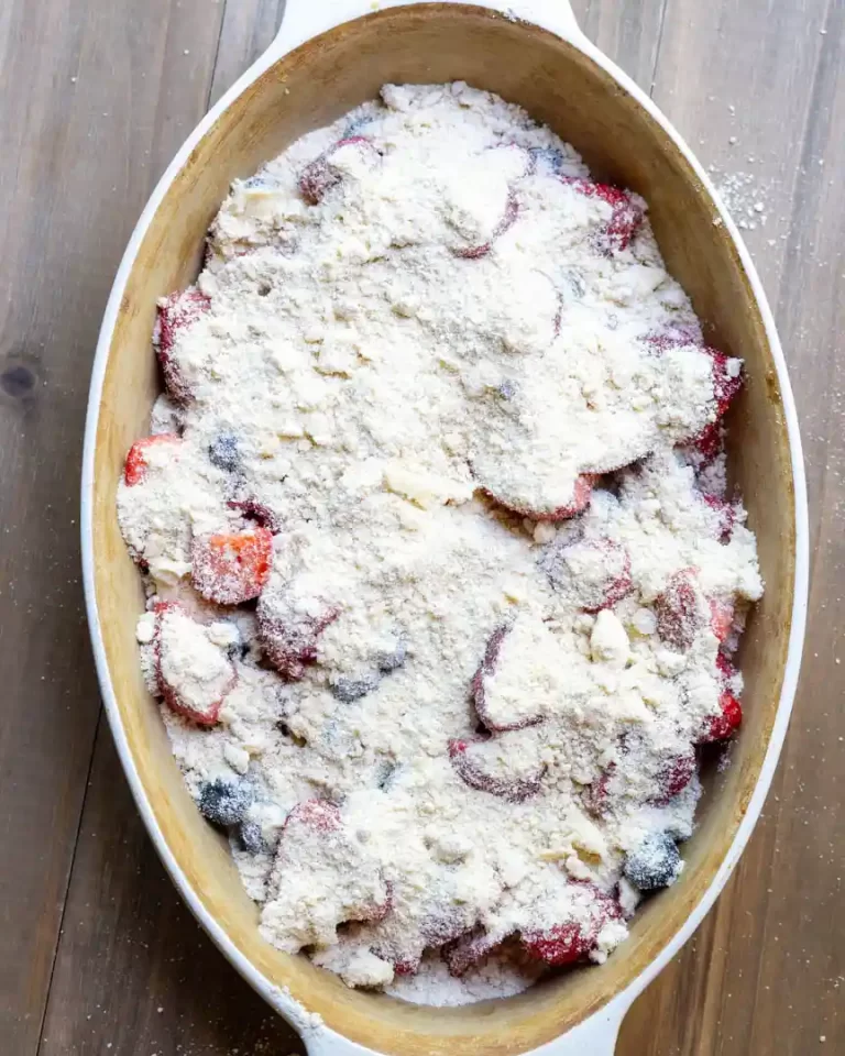 An oval baking dish with mixed berry crumble unbaked.