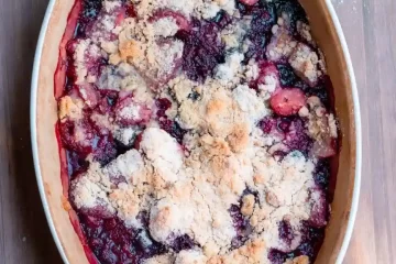 An oval baking dish with a baked mixed berry crumble.