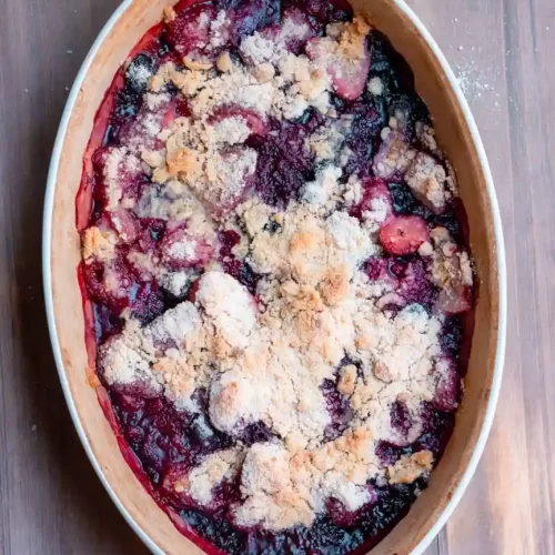 An oval baking dish with a baked mixed berry crumble.