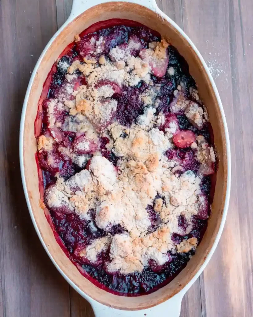 An oval baking dish with a baked mixed berry crumble.