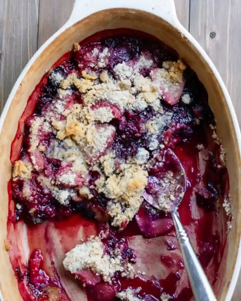 A small amount of baked mixed berry crumble left in the baking pan with a spoon.