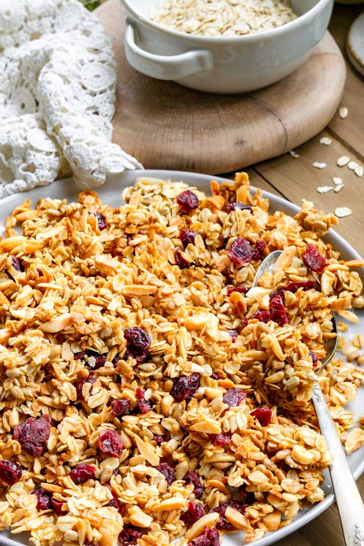 A plate with cherry & almond granola on it. There is a spoon on the plate with granola on it.