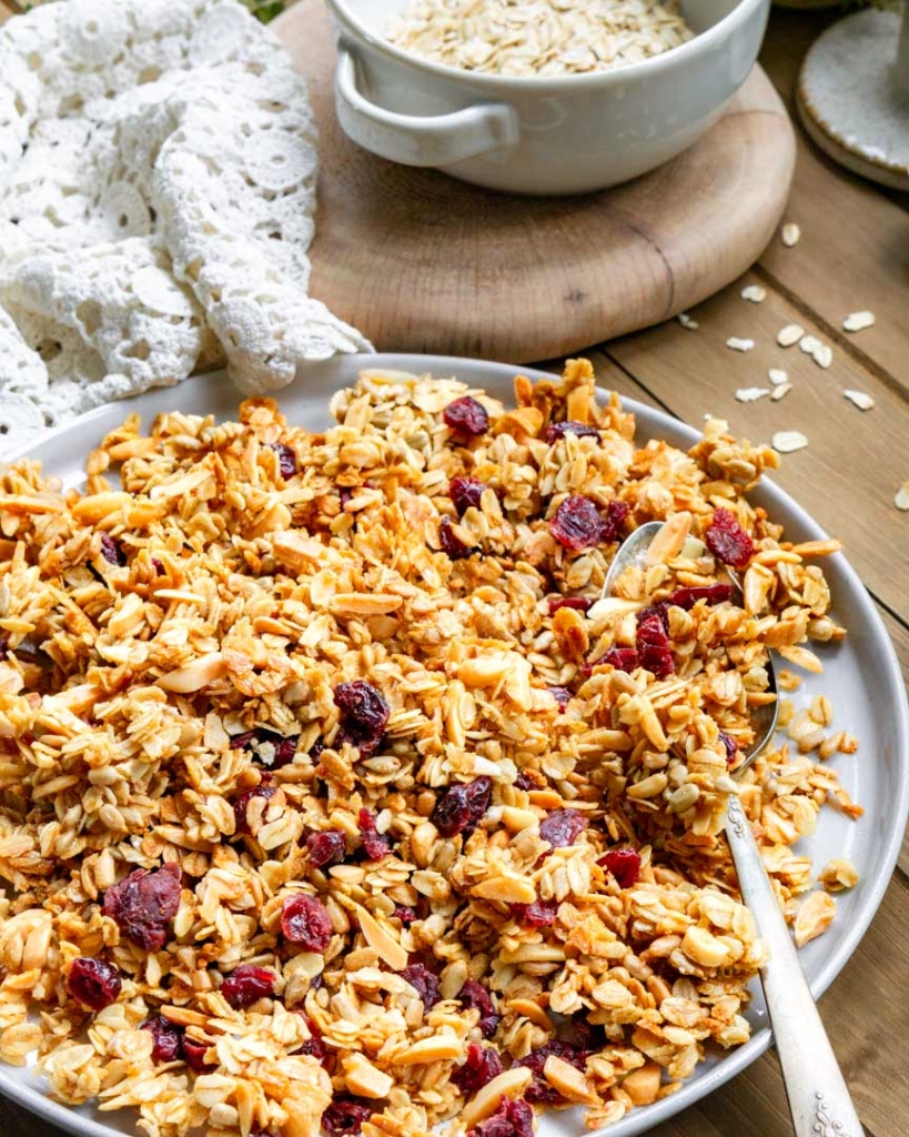 A plate with cherry & almond granola on it. There is a spoon on the plate with granola on it.