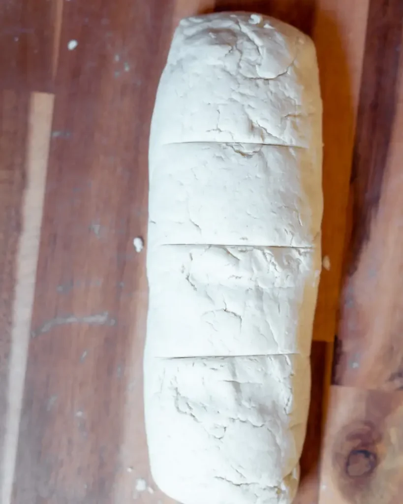 A log of raw dough with lines on top to guide cutting into even pieces.