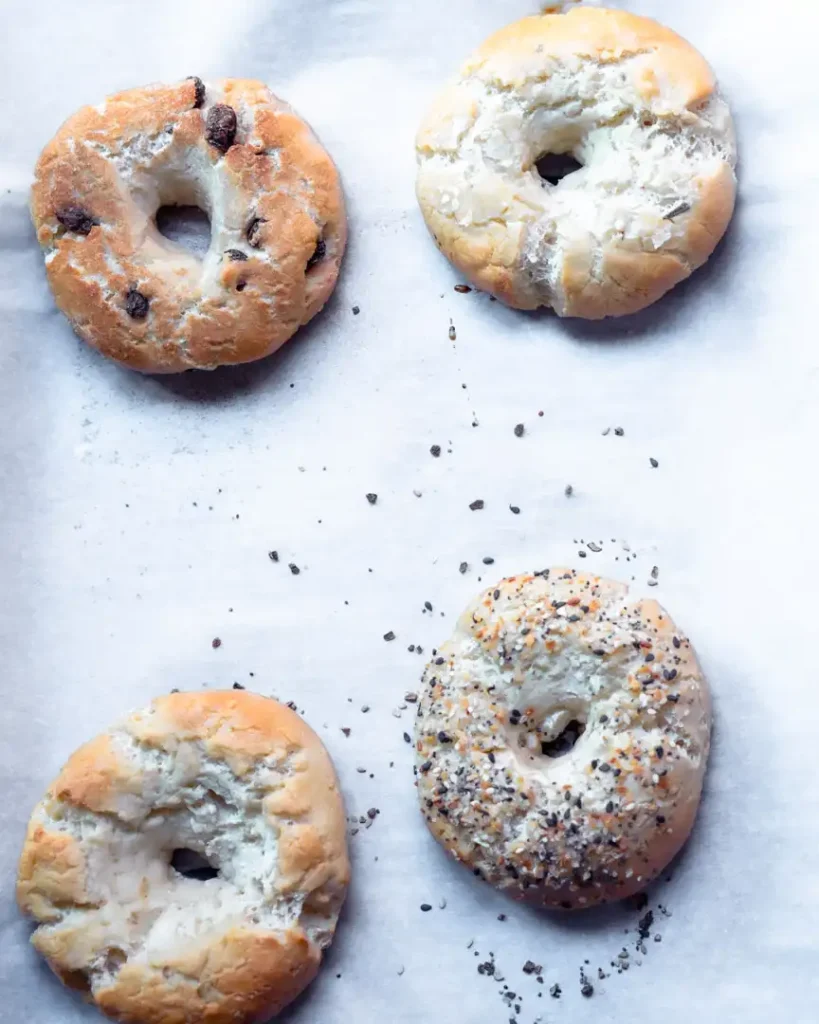 Baked assorted bagels on a baking sheet.