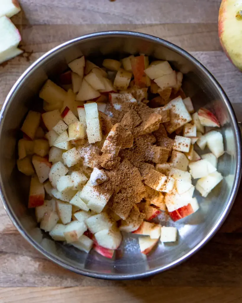 Chopped apples topped with spices in a pot.