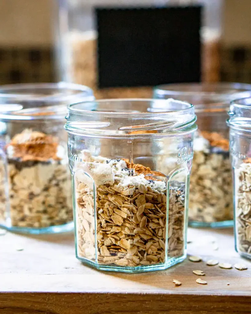 A jar half filled with dried oats and spices.