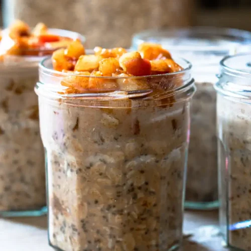 Several jars of overnight oats topped with sautéed apples.